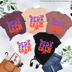 May include: Five t-shirts with the text "PEDS CREW" in a retro font. The shirts are in various colors, including maroon, peach, white, and black. The text is in purple and orange.