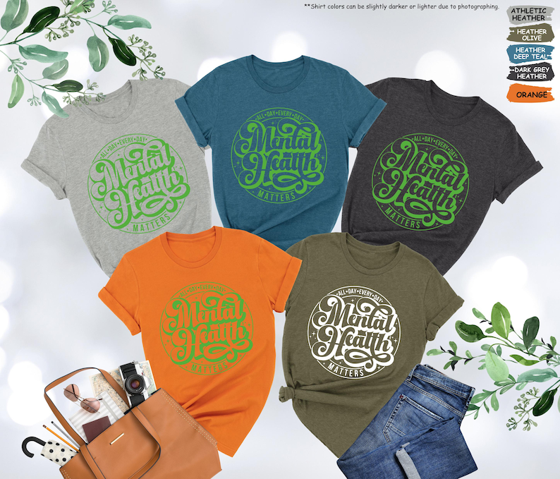May include: Five t-shirts in different colors with a green graphic that says "Mental Health Matters" in a retro font.