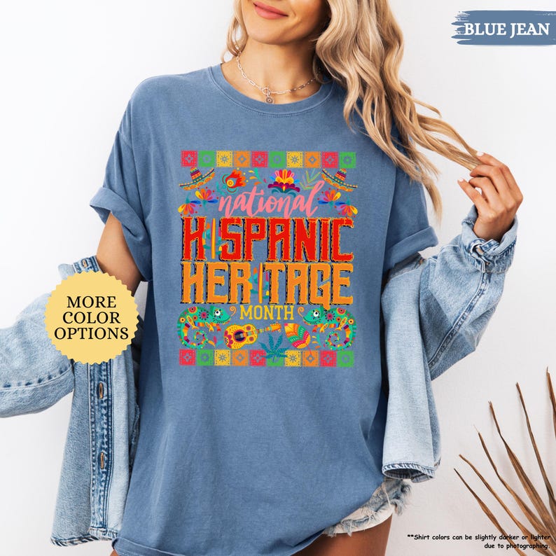 Peut inclure: T-shirt bleu jean avec l'inscription "national HISPANIC HERITAGE MONTH" dans un design color&eacute;. Le t-shirt pr&eacute;sente un motif festif avec des sombreros, des fleurs et d'autres &eacute;l&eacute;ments culturels. Le t-shirt est de style d&eacute;contract&eacute; et confortable.