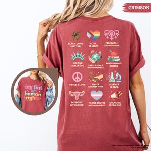 May include: Crimson-colored t-shirt with various social justice graphics and text. The shirt features phrases like "Black Lives Matter," "Love is Love," and "Trans Rights are Human Rights." The shirt also has the text "big fan of human rights."