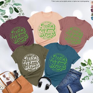 May include: Five different colored t-shirts with the text "All Day Every Day Mental Health Matters" in a green circle on the front.