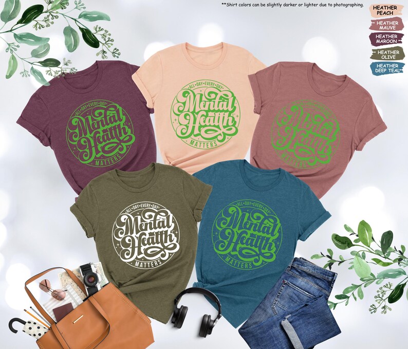 May include: Five different colored t-shirts with the text "All Day Every Day Mental Health Matters" in a green circle on the front.