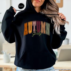 a woman wearing a black hoodie with the word autumn on it