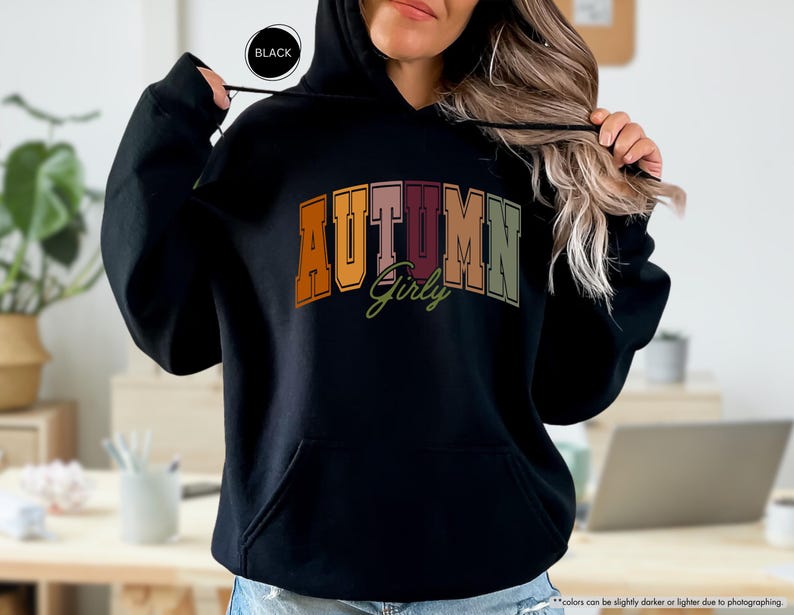 a woman wearing a black hoodie with the word autumn on it