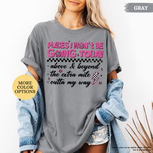 May include: Gray t-shirt with the text "PLACES I WON'T BE GOING TODAY" in pink and black. The shirt also features the phrases "above & beyond", "the extra mile", and "outta my way". A yellow circle with "MORE COLOR OPTIONS" is in the image.