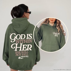 Puede incluir: Sudadera con capucha verde militar con el texto "GOD IS WITHIN HER SHE WILL NOT FALL PSALM 465" en la espalda. La parte delantera de la sudadera tiene el texto "Psalm 465". La sudadera tiene capucha y bolsillo delantero.