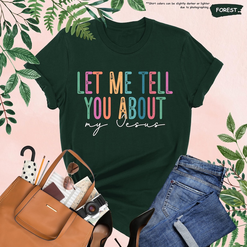 May include: A dark green t-shirt with the text "LET ME TELL YOU ABOUT my Jesus" in rainbow colors. The text is in a retro font style.