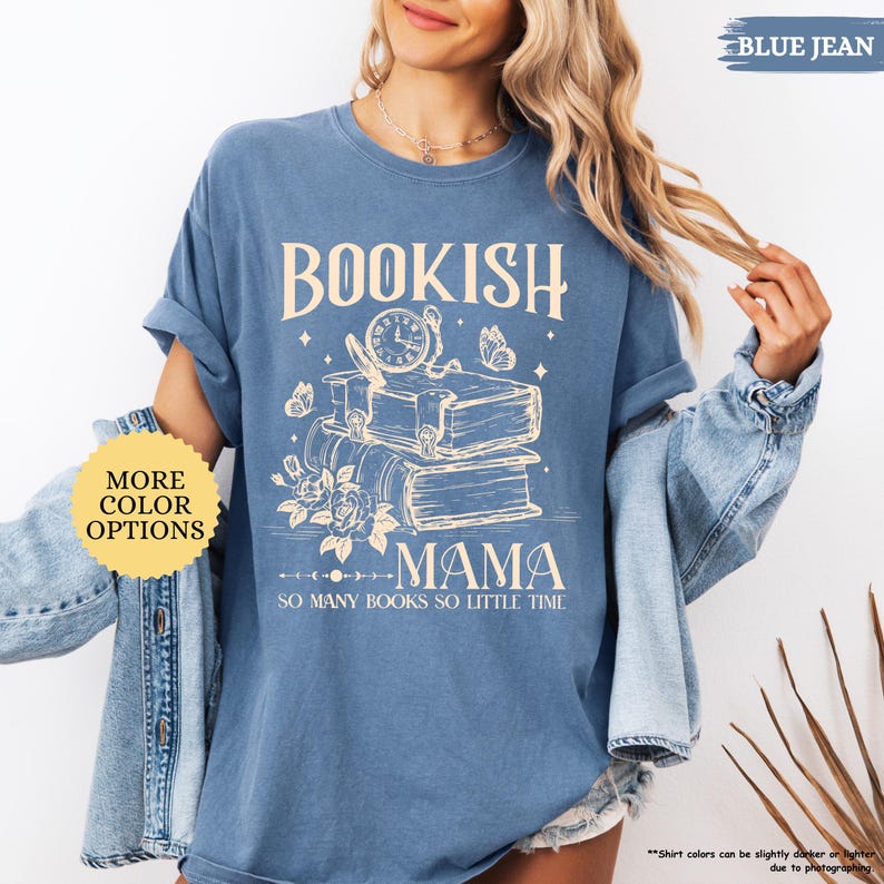 May include: Blue jean-coloured t-shirt with the text "BOOKISH MAMA" and the phrase "SO MANY BOOKS SO LITTLE TIME." The design features a stack of books, a clock, butterflies, and flowers. The shirt has rolled-up sleeves.