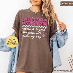 May include: Espresso-colored t-shirt with the text "PLACES I WON'T BE GOING TODAY" in pink and white. The shirt features a checkered flag design and additional phrases like "above & beyond" and "outta my way".