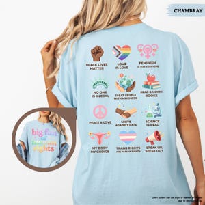 May include: Light blue t-shirt with various graphic designs and text, including "Black Lives Matter," "Love is Love," and "Feminism is for Everyone." The shirt also features the text "big fun of human rights" on the front. The shirt is made of a soft material.