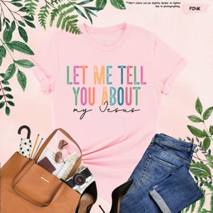 May include: Pink t-shirt with the text "LET ME TELL YOU ABOUT my Jesus" in rainbow colors.