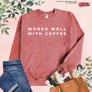 May include: Heather scarlet red sweatshirt with the text "WORKS WELL WITH COFFEE" in white.
