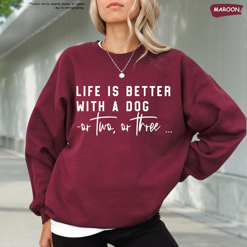 May include: A maroon sweatshirt with the text "LIFE IS BETTER WITH A DOG -or two, or three..." printed in white.