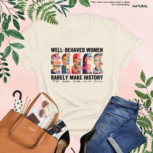 May include: A white t-shirt with a graphic print of four women's faces and the text "Well-Behaved Women Rarely Make History". The text is in black and the women's faces are in various colors. The women's names are listed below their faces.