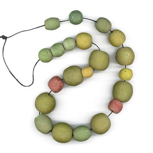 May include: A string of green, yellow, and red wooden beads on a black cord. The beads are various shades of green, yellow, and red, and some have a slightly textured surface.