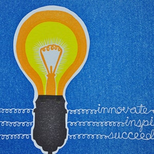 May include: A yellow light bulb with an orange outline on a blue background. The words "innovate", "inspire", and "succeed" are written in white cursive below the light bulb.