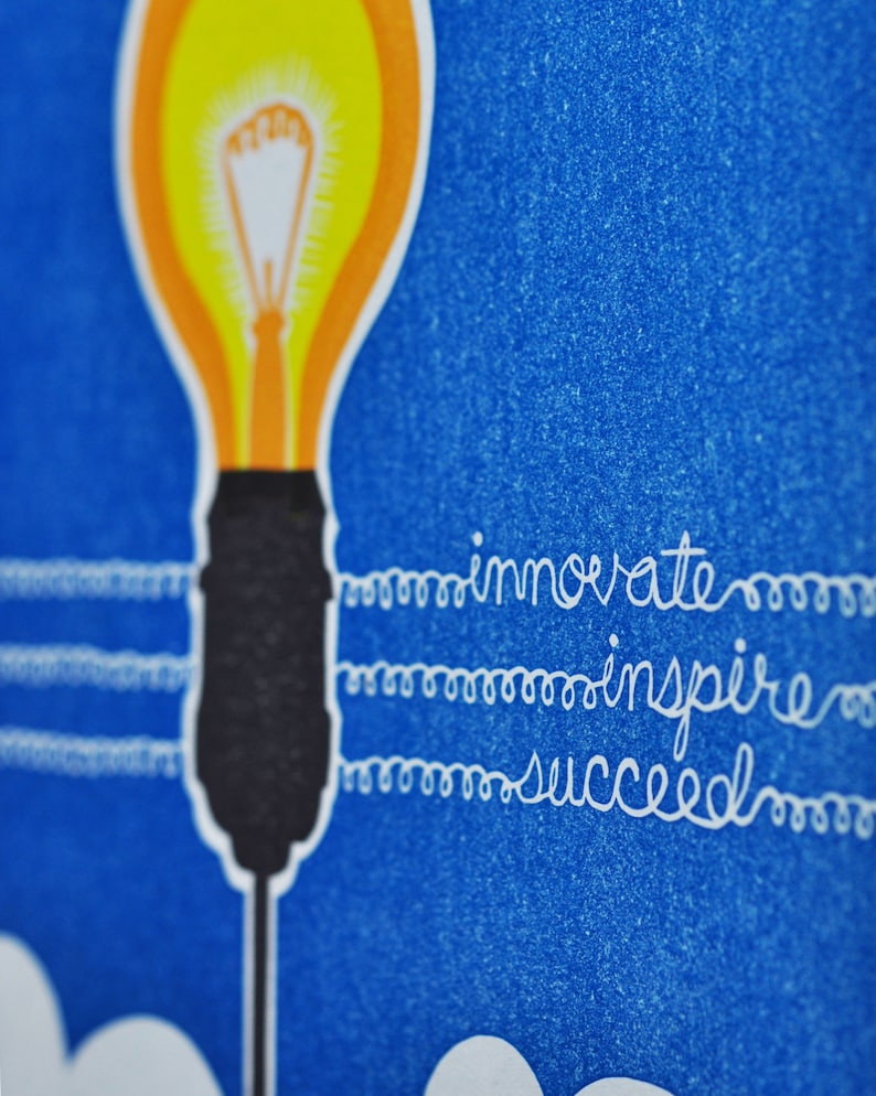 May include: A yellow light bulb with a black base and a white cord. The cord has the words "innovate", "inspire", and "succeed" written on it.