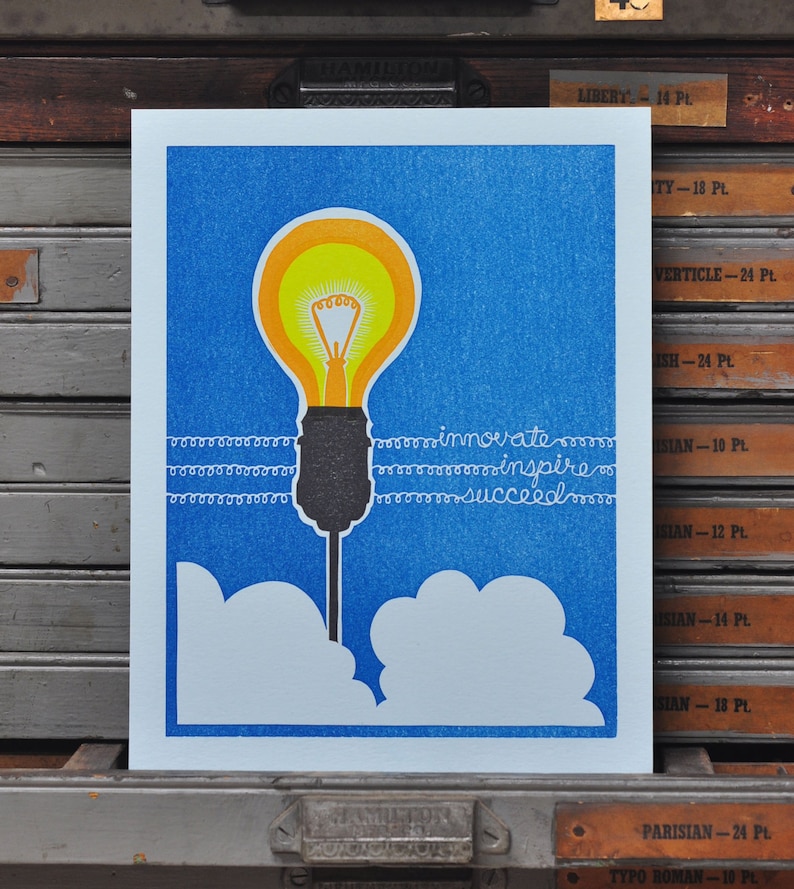 May include: A blue and white print with a yellow light bulb, white clouds, and the text "innovate inspire succeed".