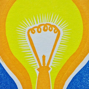 May include: A yellow light bulb with an orange outline, set against a blue background. The light bulb has a white center and a radiating pattern of white lines.