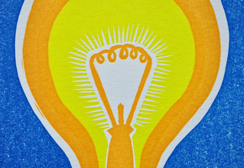 May include: A yellow light bulb with an orange outline, set against a blue background. The light bulb has a white center and a radiating pattern of white lines.