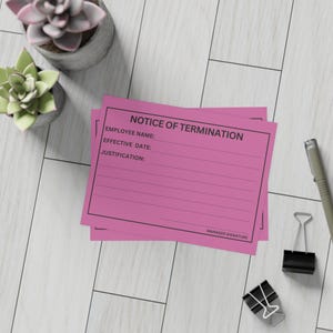 Peut inclure: Deux formulaires roses « Avis de licenciement » avec texte noir, empilés sur une surface à grain de bois blanc. Les formulaires comportent des lignes pour le nom de l'employé, la date d'effet et la justification. Un stylo, des pinces à reliure et des plantes succulentes en pot sont également visibles.