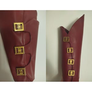 May include: Close-up of a red leather boot with gold metal buckles. The boot has a pointed toe and a high heel.