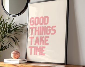 Può includere: Una stampa incorniciata con sfondo bianco e cornice nera. La stampa presenta il testo "GOOD THINGS TAKE TIME" in rosa.