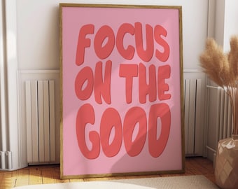 Può includere: Un poster incorniciato rosa con il testo "FOCUS ON THE GOOD" in lettere rosse e grassetto.