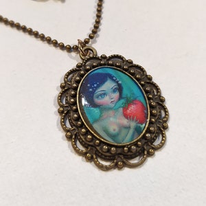 May include: A bronze necklace with a cameo pendant featuring a cartoon illustration of Snow White holding a red apple. The cameo is surrounded by a decorative filigree frame.