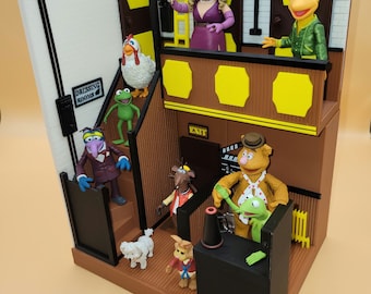May include: A multi-level playset featuring characters from the Muppets, including Miss Piggy, Kermit the Frog, Fozzie Bear, and Animal. The playset includes a dressing room, a stage, and a control room. The playset is made of plastic and is painted in bright colors.