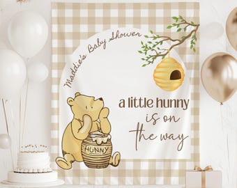 May include: A baby shower backdrop featuring a cartoon bear holding a honey pot. The backdrop has a tan and white checkered pattern with the text "Maddie's Baby Shower" and "a little hunny is on the way."