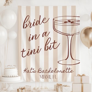 Può includere: Un fondale per un addio al nubilato con la scritta "bride in a tini bit" e un'illustrazione di cocktail. Lo sfondo ha strisce verticali beige e bianche. Palloncini bianchi e dorati, una torta e dei regali decorano la scena.