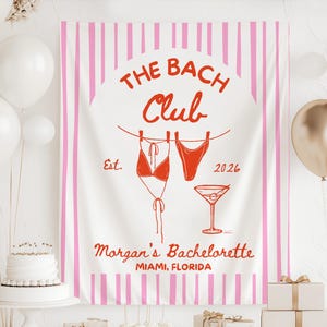 May include: A white banner with pink vertical stripes and the text "THE BACH Club" in red. Below the text are illustrations of a bikini and a martini glass. The banner also includes the text "Morgan's Bachelorette, Miami, Florida."