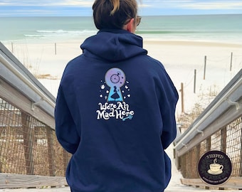 We're All Mad Here is a whimsical keyhole design on a comfy zip-up hoodie—the perfect gift for Alice in Wonderland Fans and Tea Lovers.