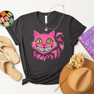 Cheshire Cat, We&#39;re All Mad Here, Trendy Graphic T-shirt in Pink, Blue, and Purple. Perfect for Alice in Wonderland fans or Tea Lover gifts