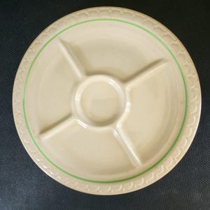 May include: A white ceramic serving plate with five sections, including a central dip bowl. The plate has a green rim and a decorative pattern.