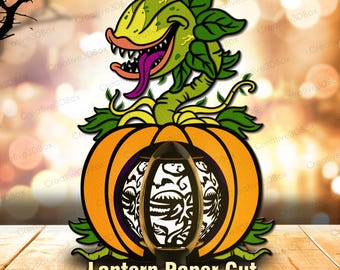 May include: A Halloween-themed paper cut design featuring a grinning, green plant monster emerging from an orange pumpkin. The design includes a decorative lantern with a black and white pattern. The text "Lantern Paper Cut" is at the bottom.