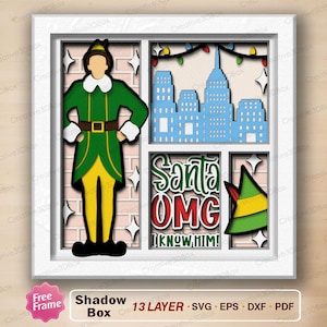 May include: A layered shadow box with a green and yellow elf, a cityscape, and the text "Santa OMG I KNOW HIM!". The artwork includes a green elf hat and string lights, all within a white frame.