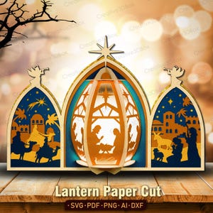 May include: A layered paper cut lantern with a nativity scene. The lantern features a central arch with a star on top, flanked by two arched panels depicting biblical scenes. The design is in shades of blue, orange, and gold, with the text "Lantern Paper Cut".