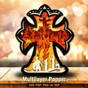 May include: A multi-layered paper cross with a detailed religious scene. The cross features a black outline, with layers of orange, yellow, and white depicting figures and structures. The text "Multilayer Papper" is at the bottom.