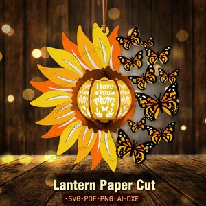 May include: A paper cut lantern design featuring a sunflower with a pumpkin-shaped center that reads "I Love You Mom". The lantern is surrounded by a ring of butterflies.