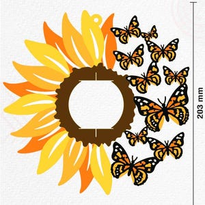 May include: A large yellow sunflower with a brown center and a circle cut out of the center.  There are 8 orange and black butterflies flying around the sunflower. The sunflower is 8 inches in diameter and the butterflies are 1 inch in diameter.