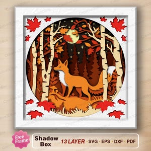 May include: A multi-layered paper shadow box art piece featuring a fox standing in a forest of birch trees. The circular design includes a full moon, pine trees, and fallen red maple leaves. The frame is white and the text reads Shadow Box.