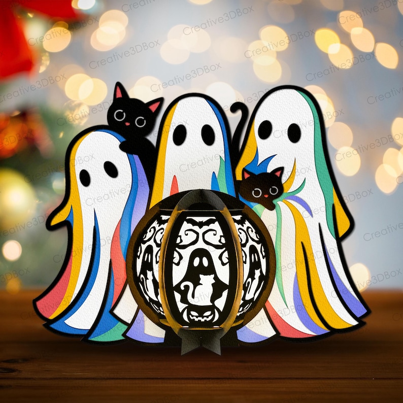 以下が含まれることがあります： ハロウィーンをテーマにしたペーパークラフト。虹色の縁取りのある3つの幽霊と2匹の黒猫が特徴です。中央には、装飾的で照らされたカボチャのランタンがあります。背景にはぼやけた光があります。