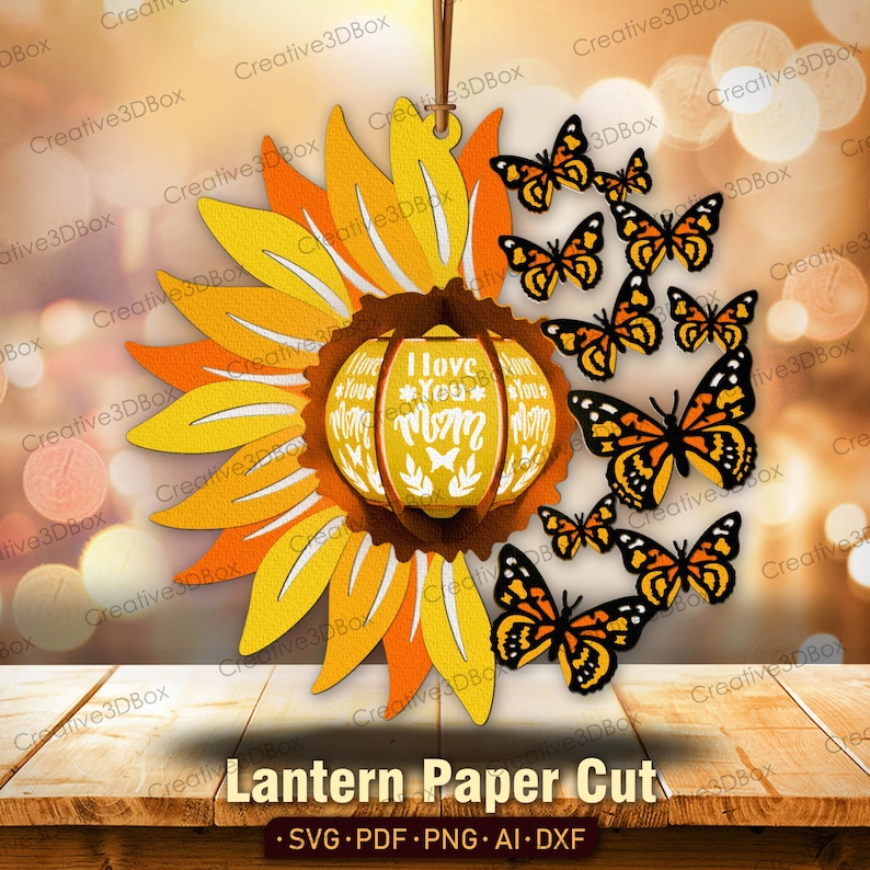 May include: A paper cut lantern design featuring a sunflower with a yellow and orange center and a pumpkin-shaped lantern with the text "I love you Mom" in the center. The lantern is surrounded by butterflies in shades of orange and brown.