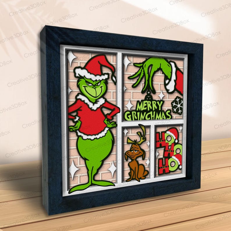 May include: A framed Christmas-themed artwork featuring the Grinch in a Santa hat, a green hand, and other festive elements. The artwork includes the text "MERRY GRINCHMAS" and is set against a brick-like background. The frame is dark blue.