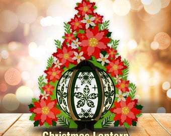 May include: A Christmas lantern shaped like a ball with a white and green design surrounded by red poinsettia flowers. The lantern is on a wooden surface. Christmas Lantern - SVG - PDF - PNG - AI - DXF
