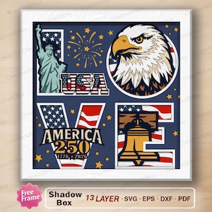 Può includere: Un design patriottico per scatola ombra con la parola "LOVE" composta da simboli americani. Include la Statua della Libertà, la bandiera USA, un'aquila, la Liberty Bell e il testo "AMERICA 250 1776-2026". Il design è su sfondo blu.