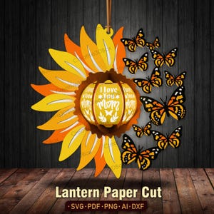 May include: A paper cut lantern design featuring a sunflower with a pumpkin-shaped center that reads "I Love You Mom". The lantern is surrounded by orange and black butterflies.