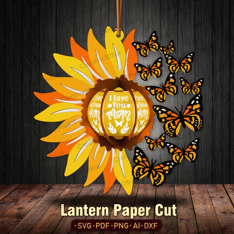 May include: A paper cut lantern design featuring a sunflower with a pumpkin-shaped center that reads "I Love You Mom". The lantern is surrounded by orange and black butterflies.
